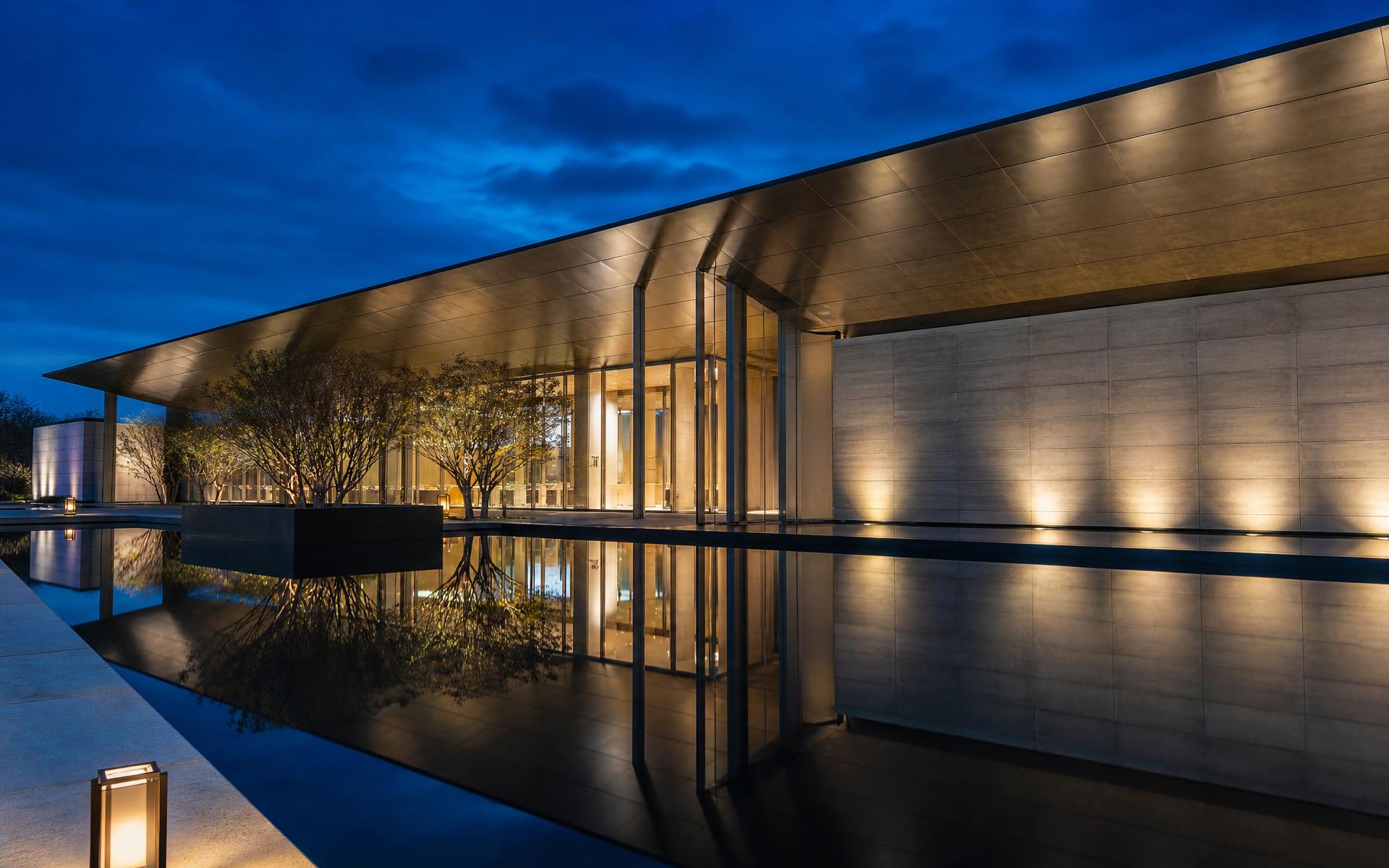 Pabellón de arquitectura contemporánea con lámina de agua a la hora azul